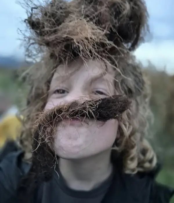 Nasmejan otrok z brki iz mahu in korenin
